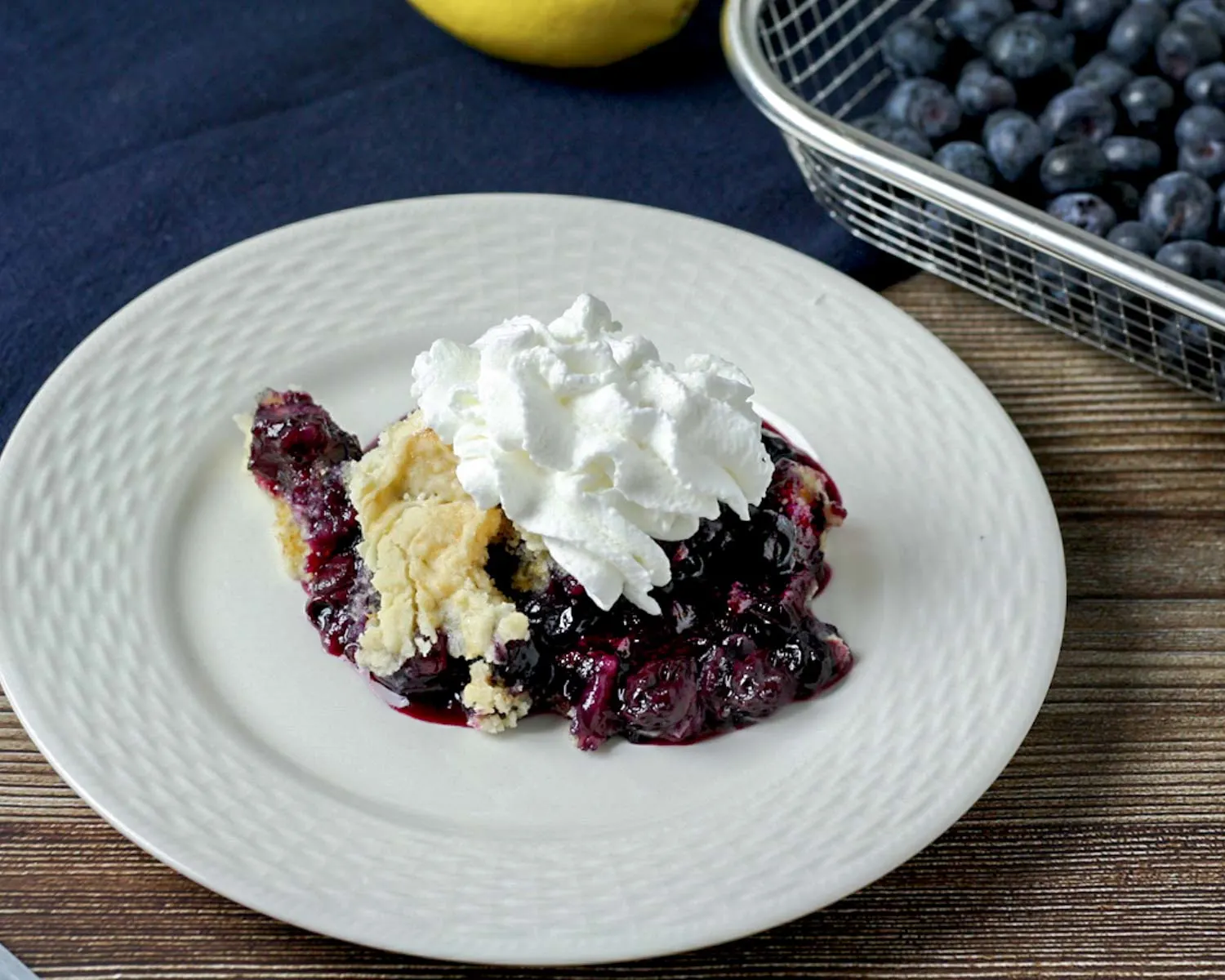 single slice of blueberry lemon dump cake with whipped cream on top.