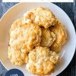 Top down view of golden baked honey butter biscuits piled on a white plate. Hostess At Heart