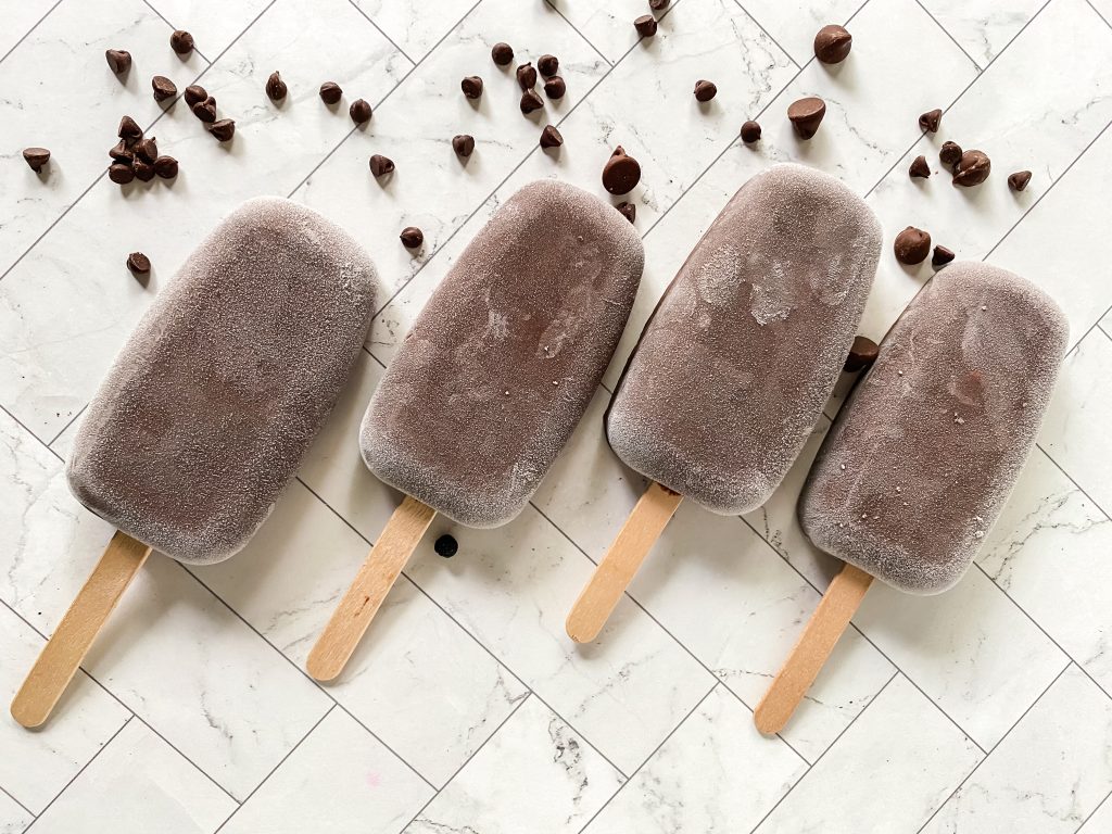 Top down view of 4 frozen fudgesicles surrounded by chocolate chips