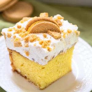 Side view of a lemon cake topped with whipped topping and crumbled cookies.