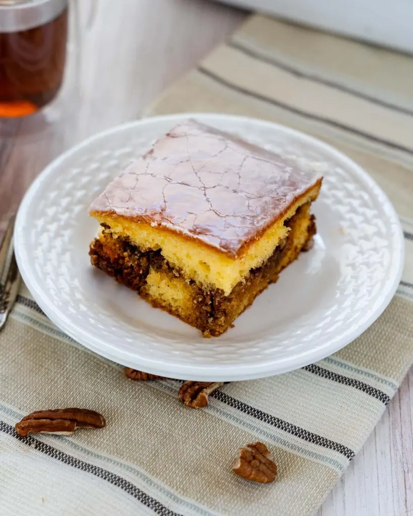 3/4 view of a slice of cake with a layer of cinnamon pecan filling and glazed with a thin sugar glaze.