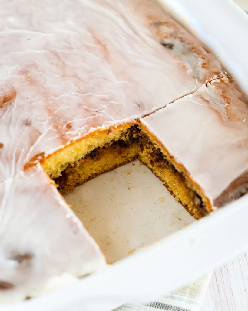 Top down view of a cake with one slice removed showing a cinnamon pecan filling.