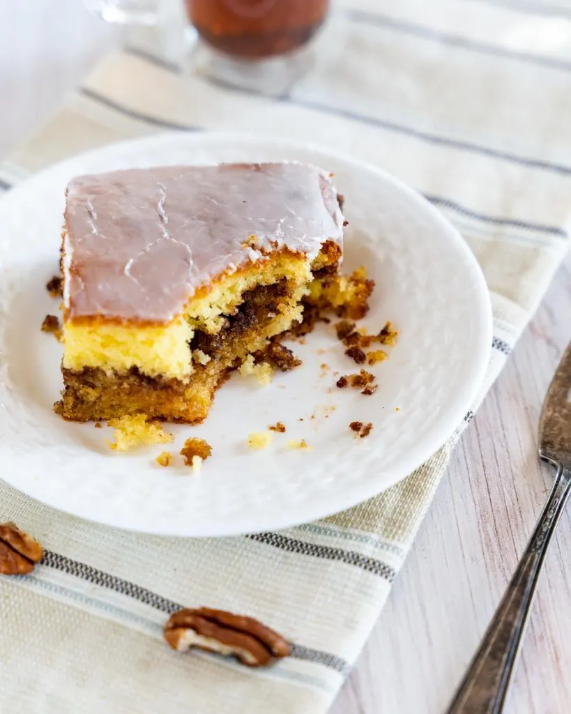 A slice of cake with a bite taken out of it showing a layer of cinnamon pecan filling.