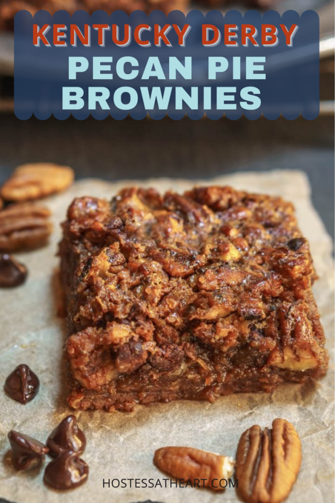 3/4 angle of a pecan pie brownie bar sitting on a piece of parchment paper surrounded by chocolate chips and pecans.