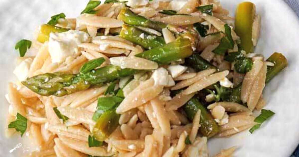 3/4 view of a plate holding wheat orzo pasta, feta, and asparagus.