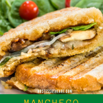 A sliced sandwich showing melted cheese, mushrooms, onions, and spinach.