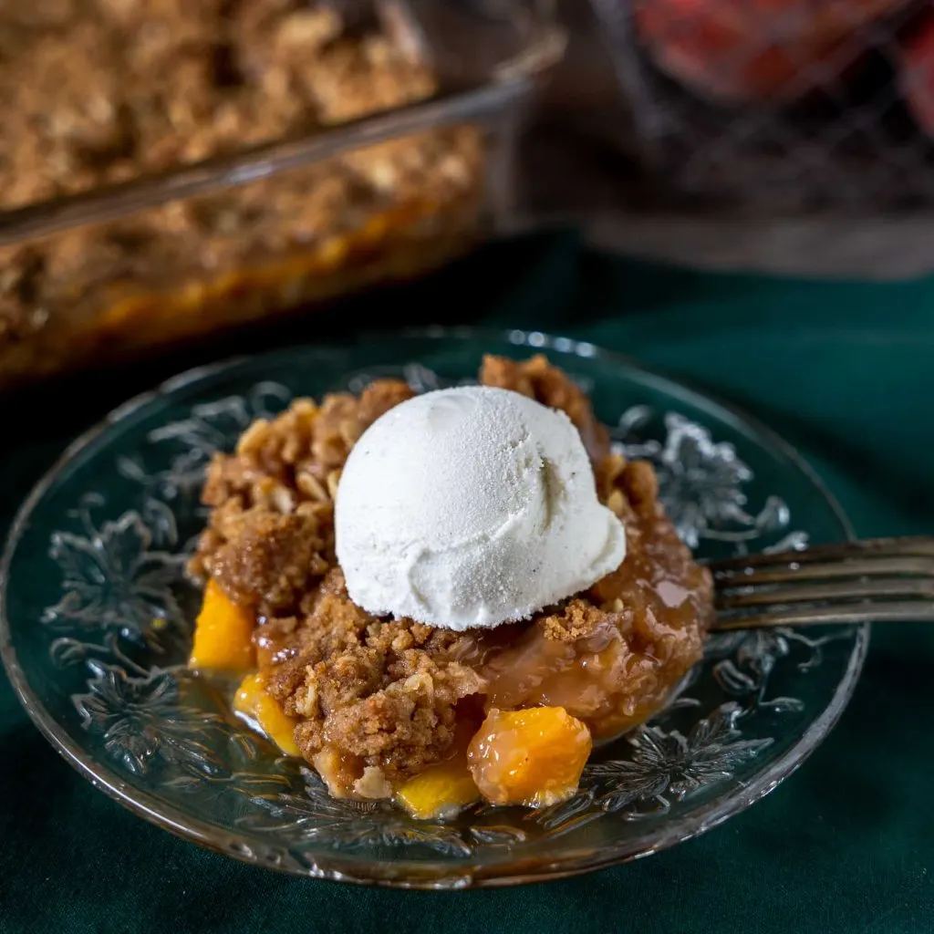 Beautiful close-up of a single serving of peach crumble on a plate.
