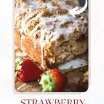 Table level photo of a loaf of Strawberry Rhubarb bread topped with streusel and glaze.