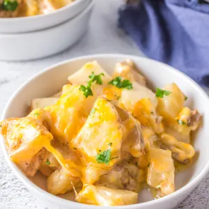 Angled view of a serving of cheesy potatoes casserole in a bowl.