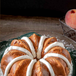 3/4 angle view of a peach bundt cake piped with frosting.