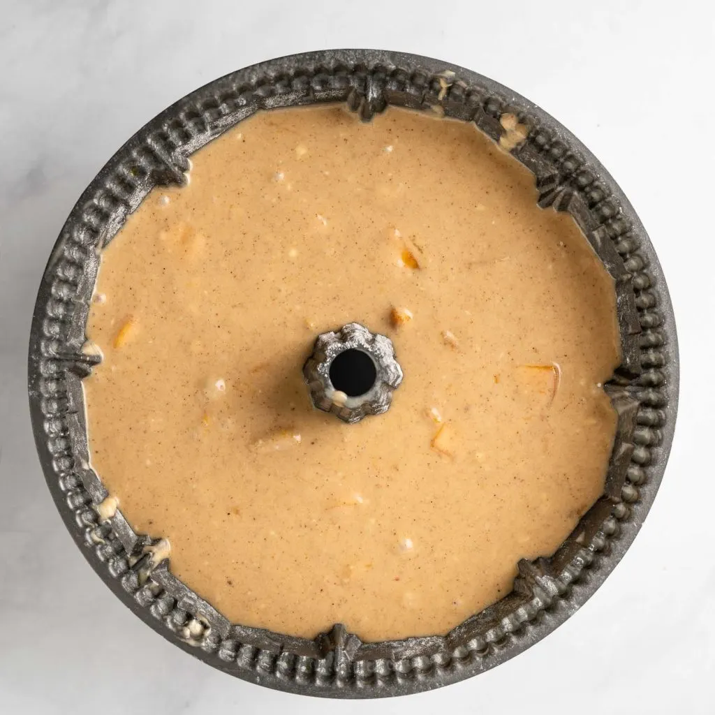 A bundt pan filled with peach cake batter.