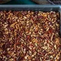 A baking dish of roasted pecans topping fresh peaches