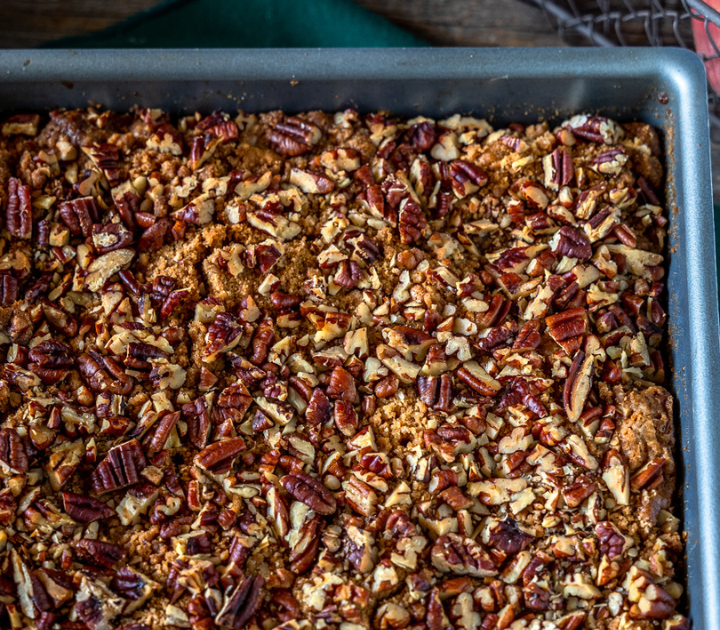 A baking dish of roasted pecans topping fresh peaches