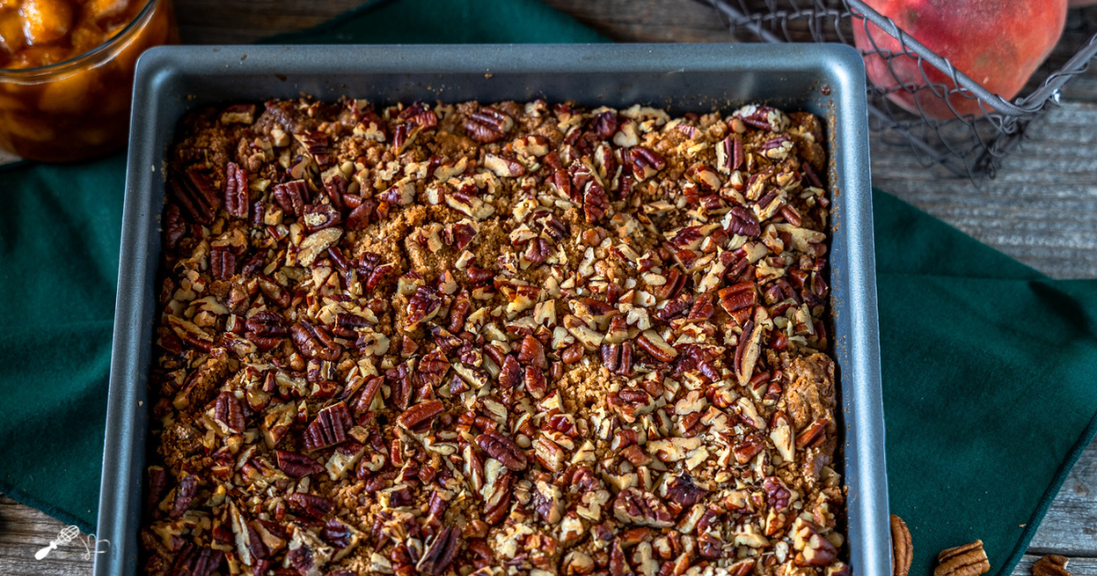 A baking dish of roasted pecans topping fresh peaches