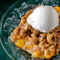 3/4 view of a slice of peach crumble recipe with oats topped with ice cream.