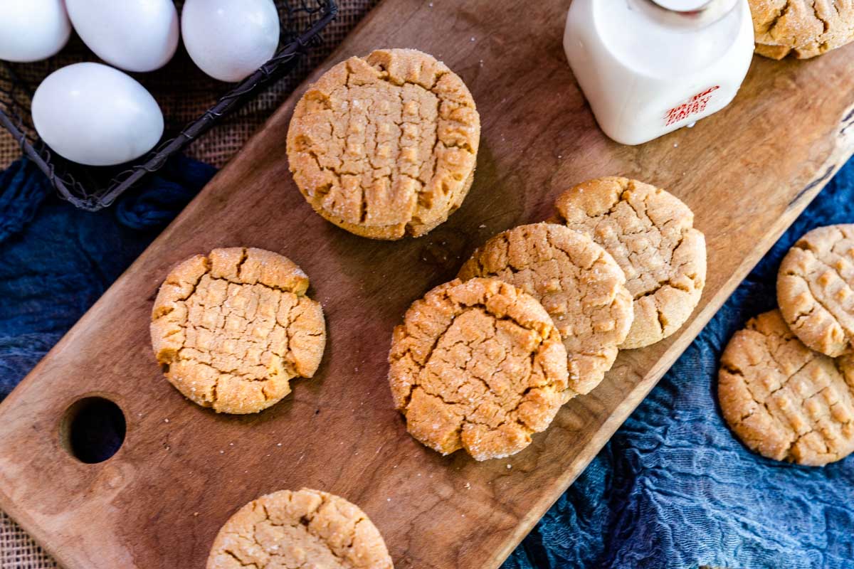 Top down view of home made peanut butter cookies sitting on a cutting board.