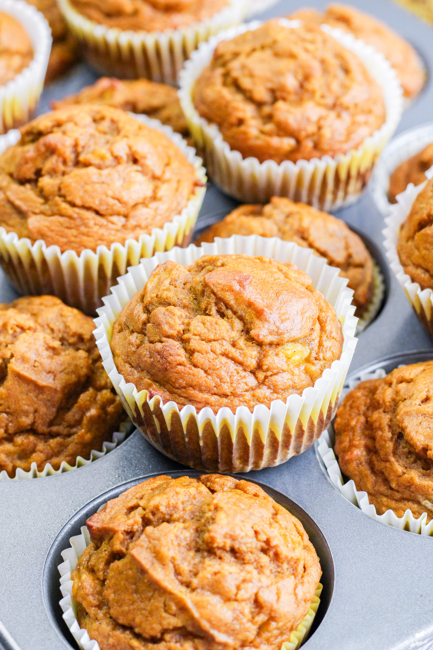 Beautifully baked pumpkin banana muffins stacked on a muffin tin. Hostess At Heart