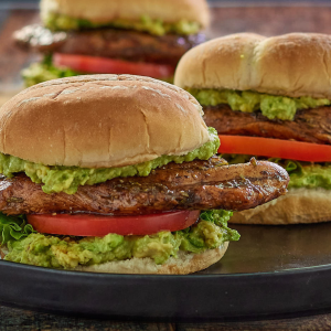 Table view of a grilled chicken breast sandwich with avocado and tomato