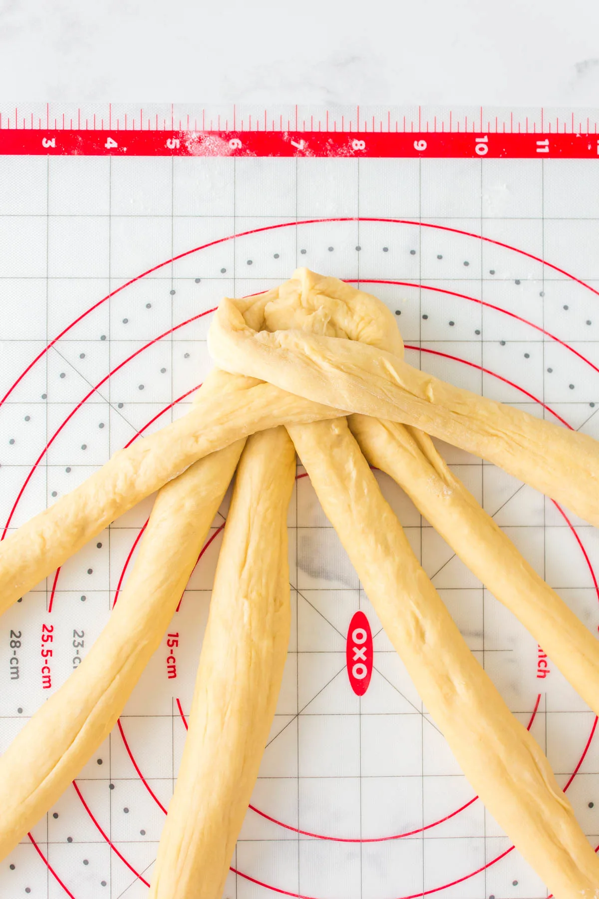 Image of challah dough strands braided together.
