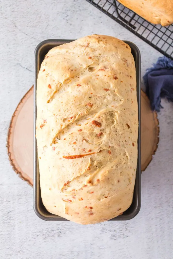 Cheddar bread loaf baked and cooling in the pan.