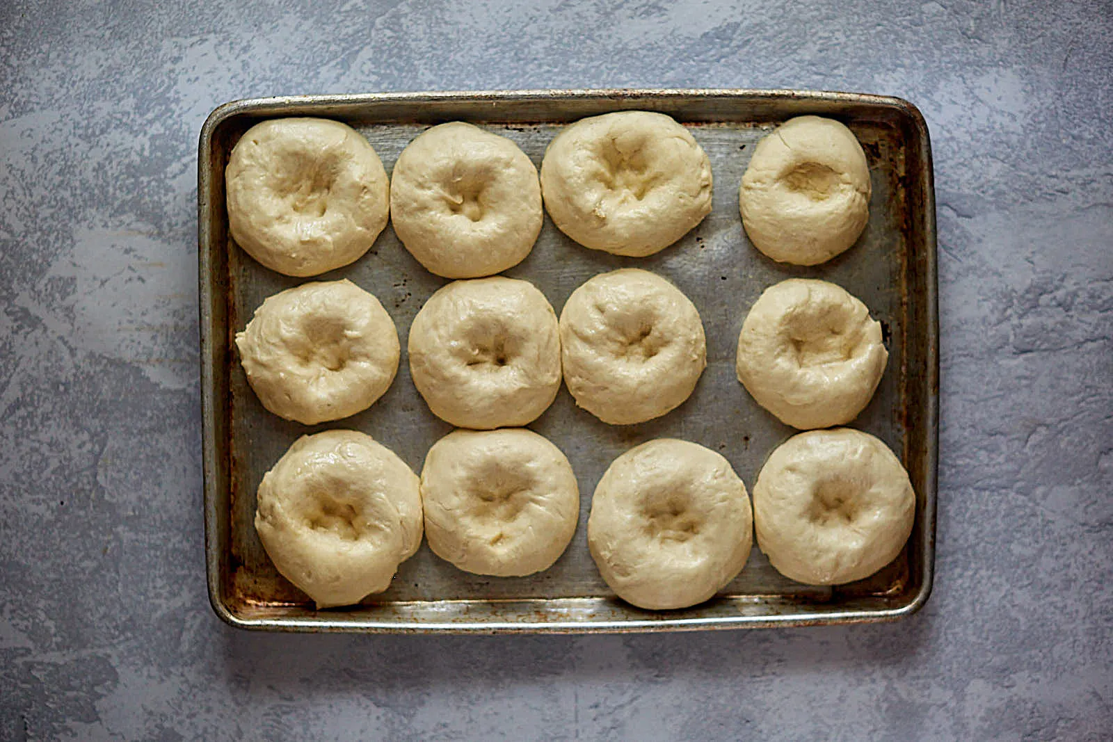 Top down view of rising kolache dough rolls with dented top.