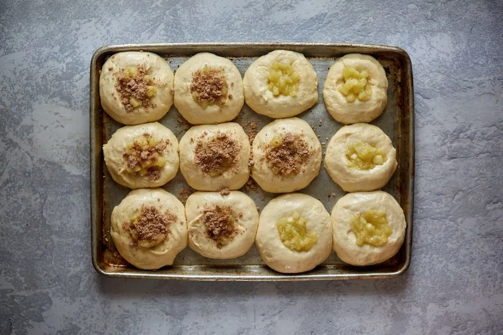 Top down view of apple filled kolaches topped with streusel topping ready to be baked.