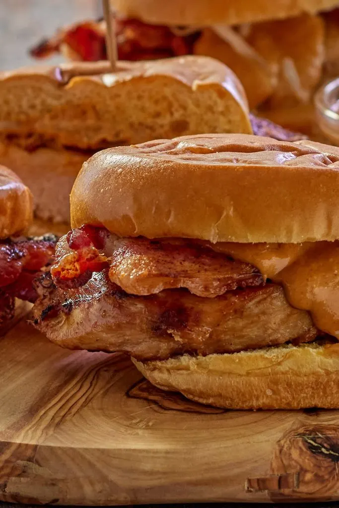 Close up of an Asian Chicken Sandwich loaded with bacon and covered in peanut sauce.