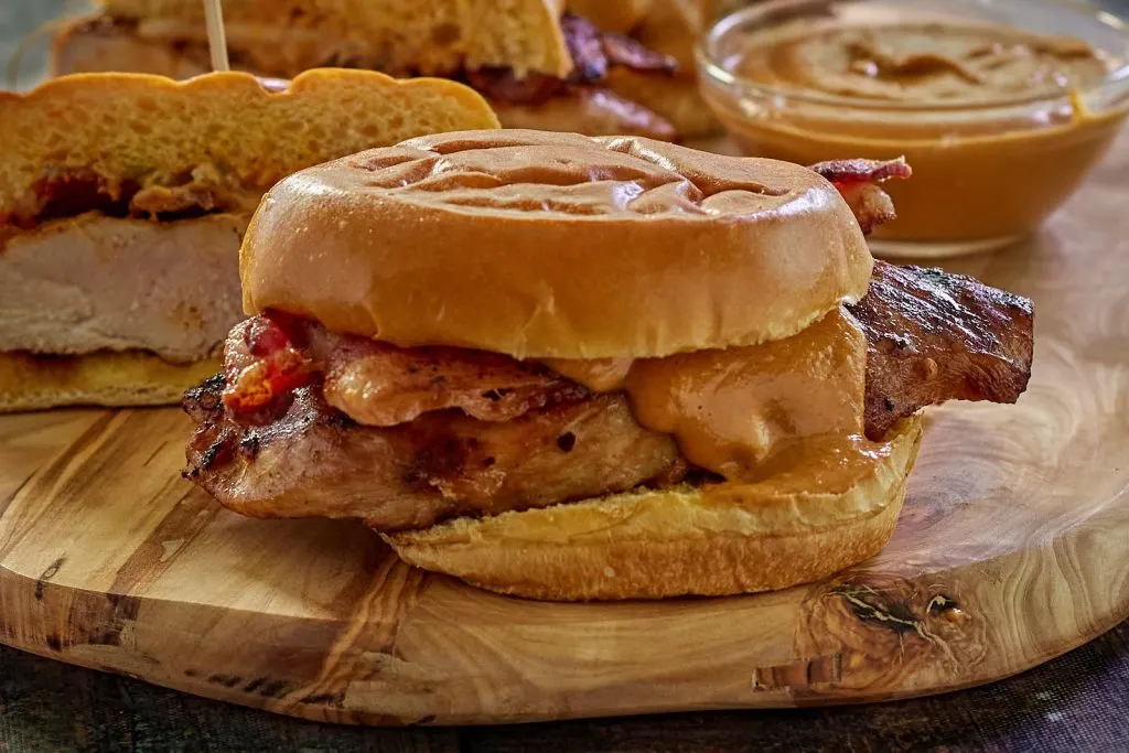 Table view angle of Thai Chicken Sandwich layered with bacon and peanut sauce.