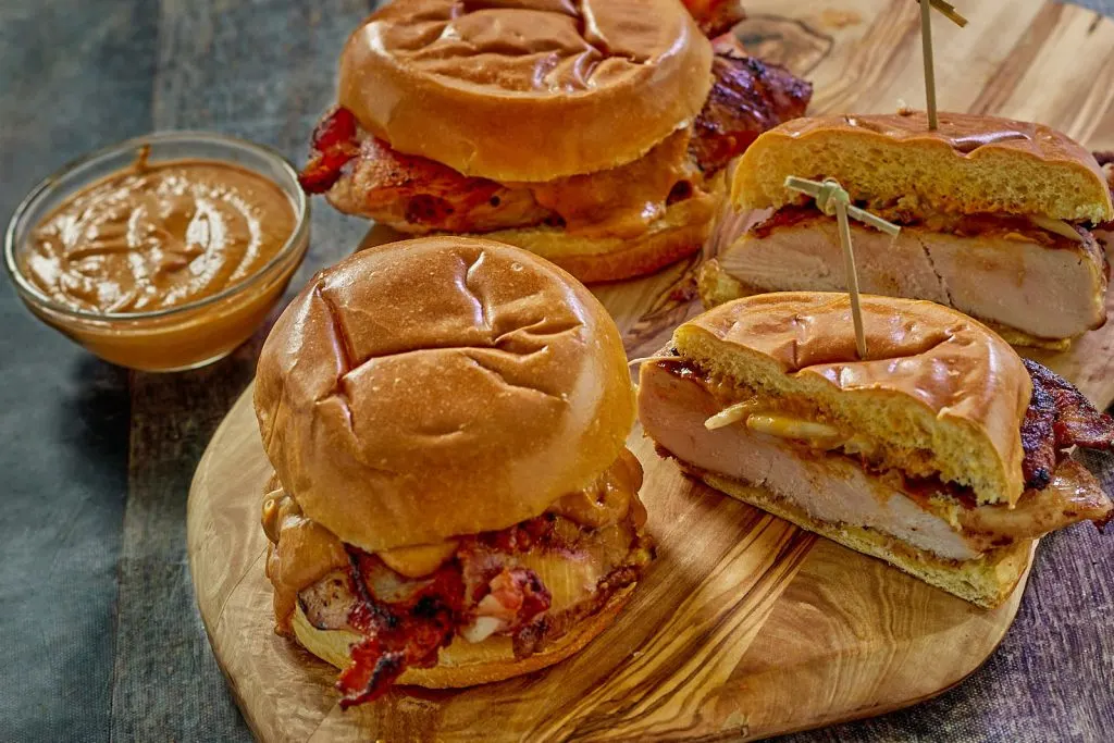 Top down view of a chicken sandwich with bacon and peanut sauce.