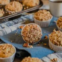 Table view of a banana walnut muffin laying on it's side surrounded by upright muffins