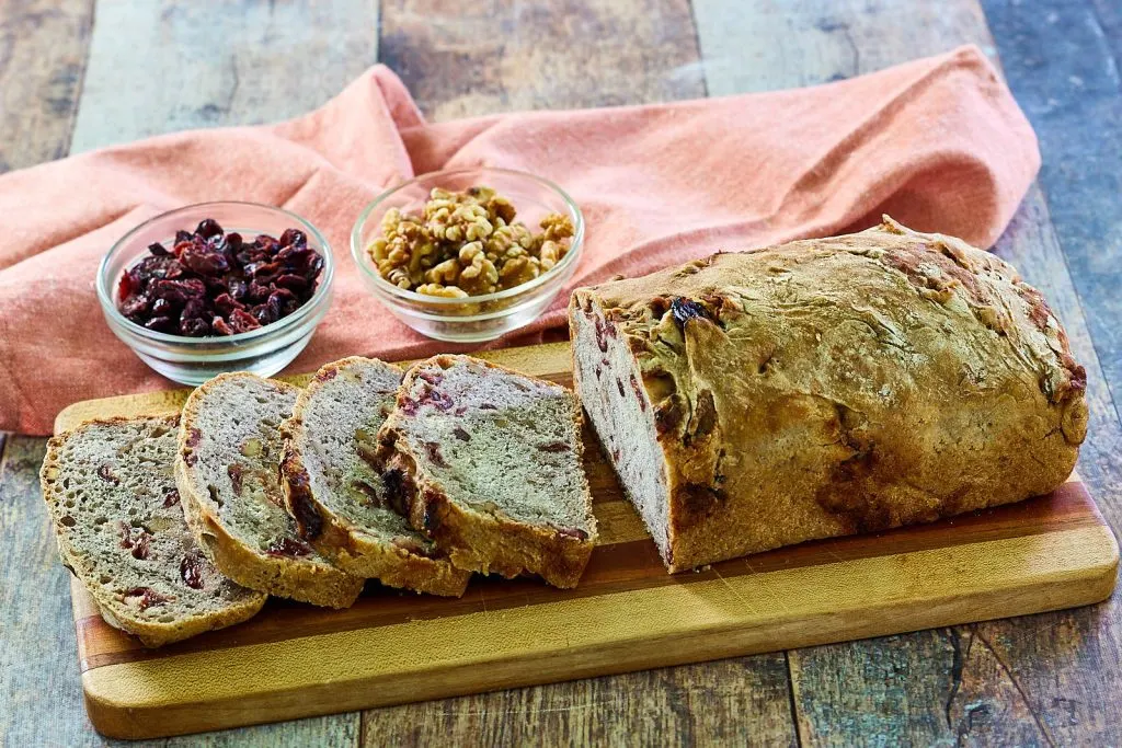 Loaf of Cranberry Walnut Bread, sliced on a tray.