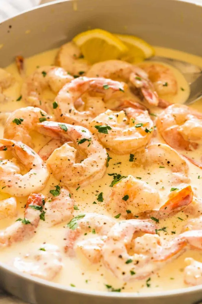 Shrimp sitting in a cream sauce in a skillet