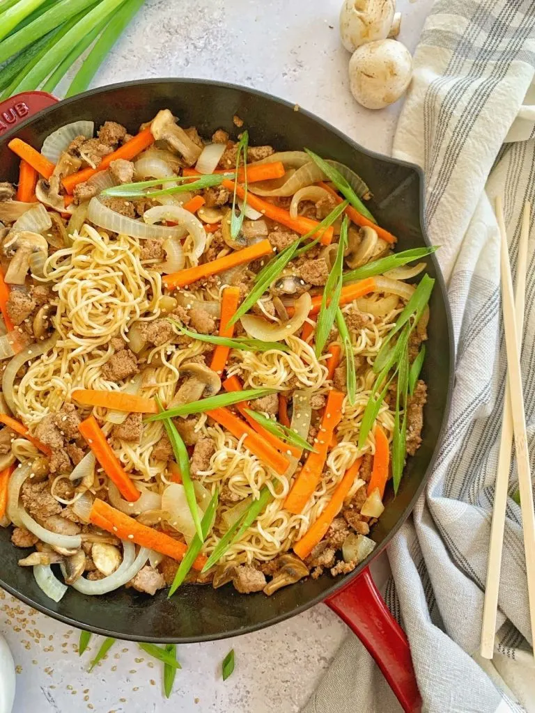 A skillet filled with ramen, turkey and vegetables.