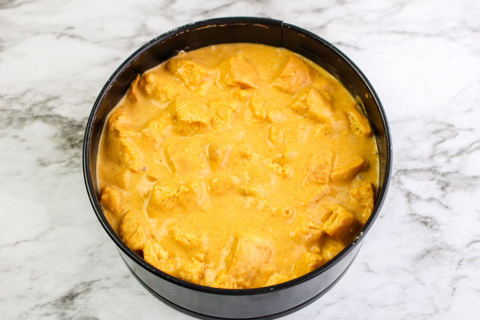 A springform pan that's been filled with pumpkin bread pudding batter. Hostess At Heart