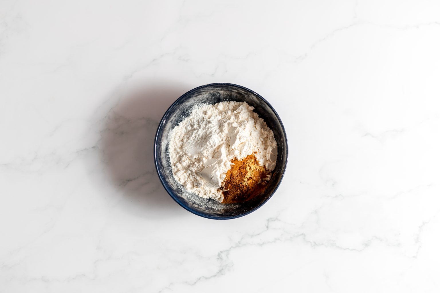 Pumpkin bread dry ingredients added to a bowl.