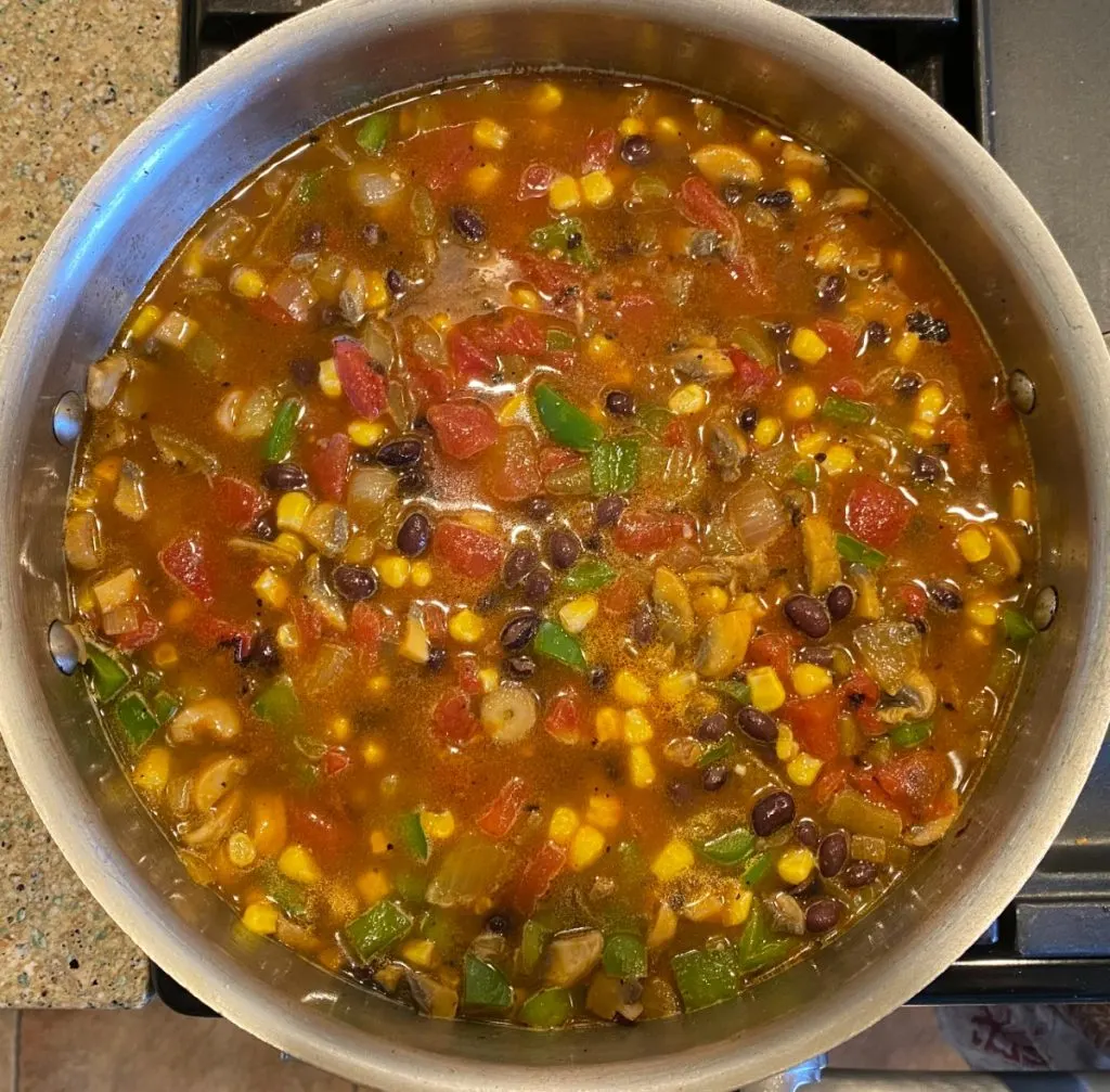 Top down view of a skillet filled with sauteed vegetables and black beens.