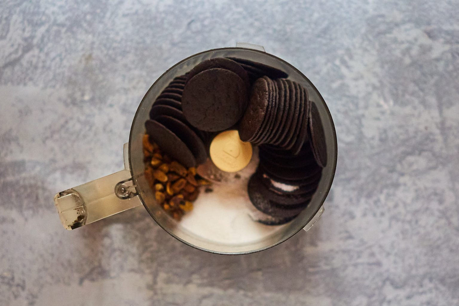 Food processor filled with cookie wafers, pistachios and sugar to make a crust.
