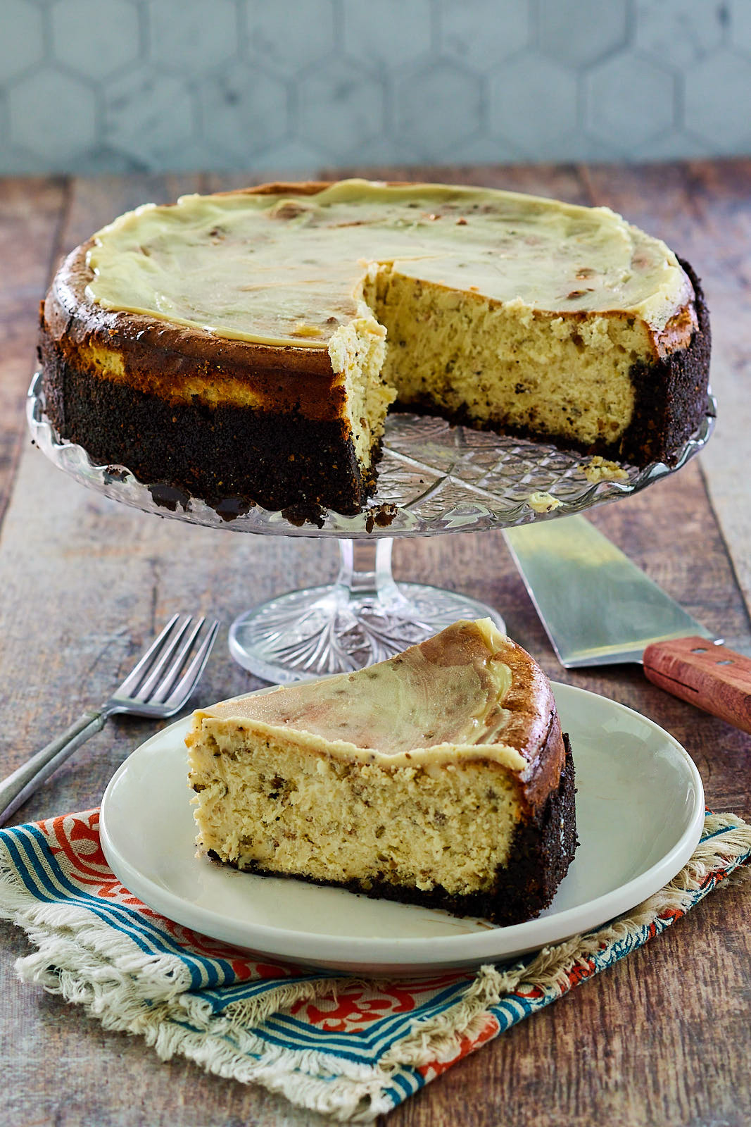 Top down view of white chocolate cheesecake with pistachios and a slice removed.