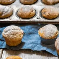 3/4 view of muffins from Pumpkin Spice Muffins Recipe dusted with powdered sugar