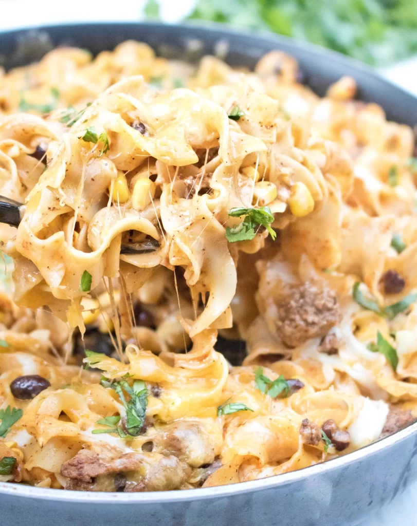 enchilada skillet pasta with a spoon pulling the melted cheese