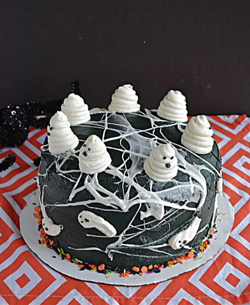Black cake topped with marshmallow spiderweb and ghosts.