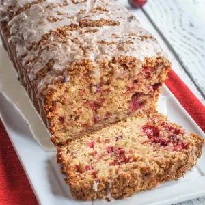 3/4 angled view of a loaf of bread loaded with dried cranberries and topped with streusel and glaze.