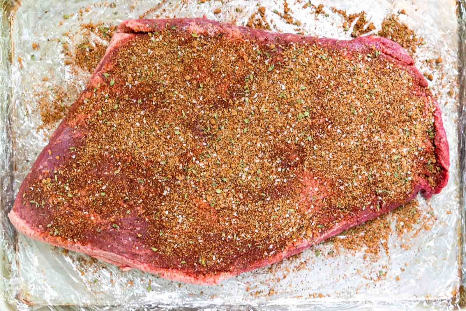 A beef brisket covered in dry rub ingredients