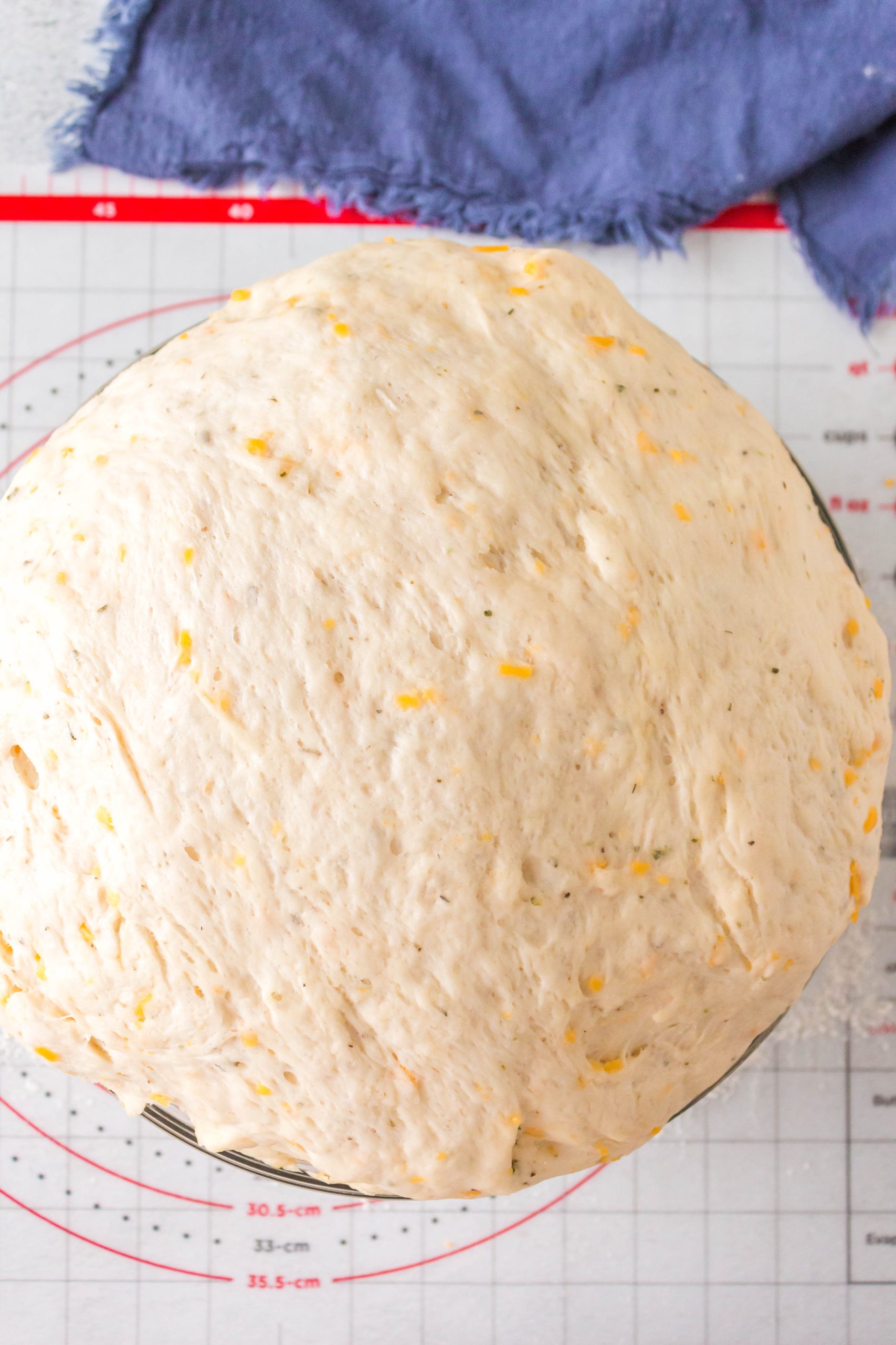 Proofed cheesy bread dough in a large bowl.