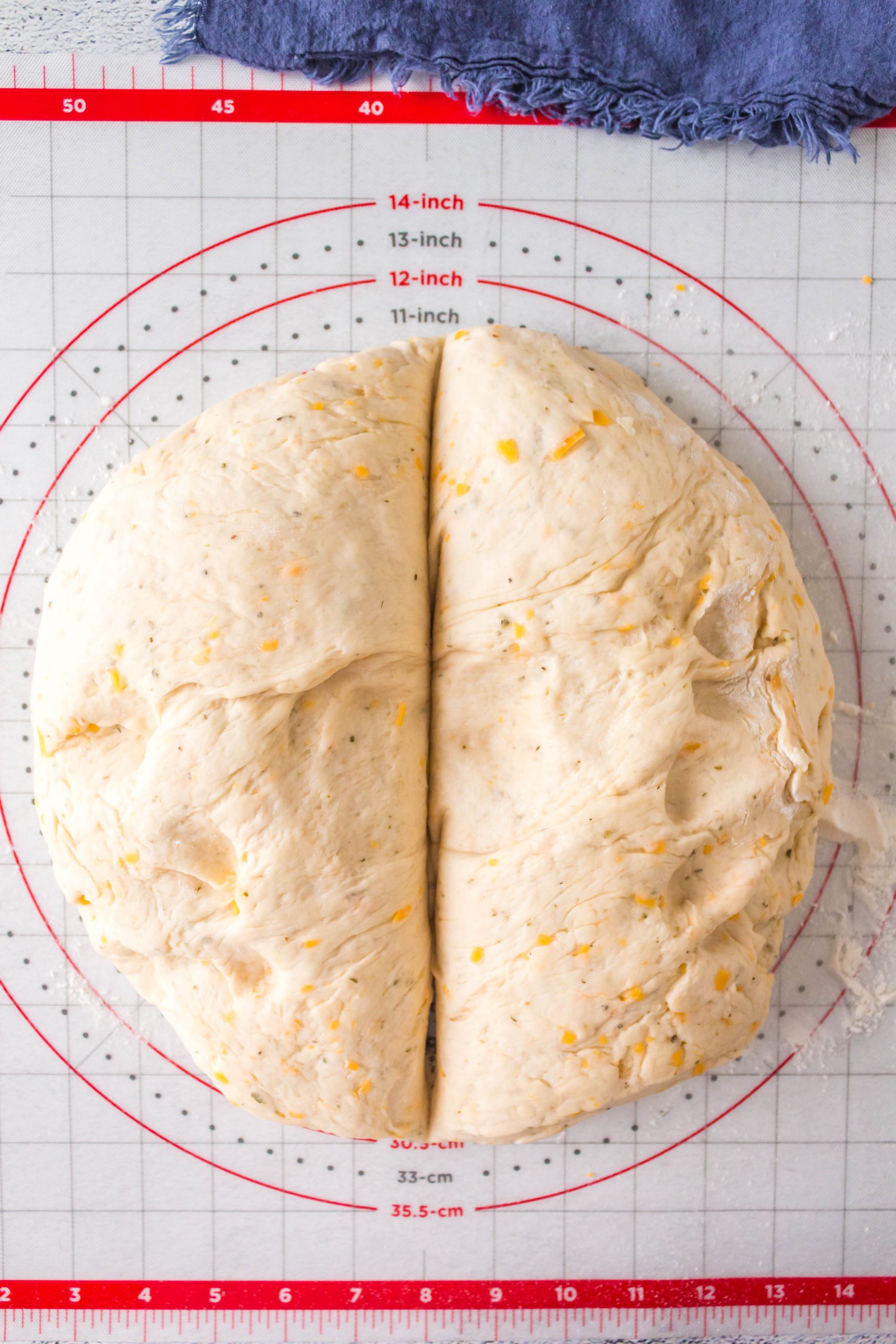 A circle of bread dough sliced in half to make two cheese loaves