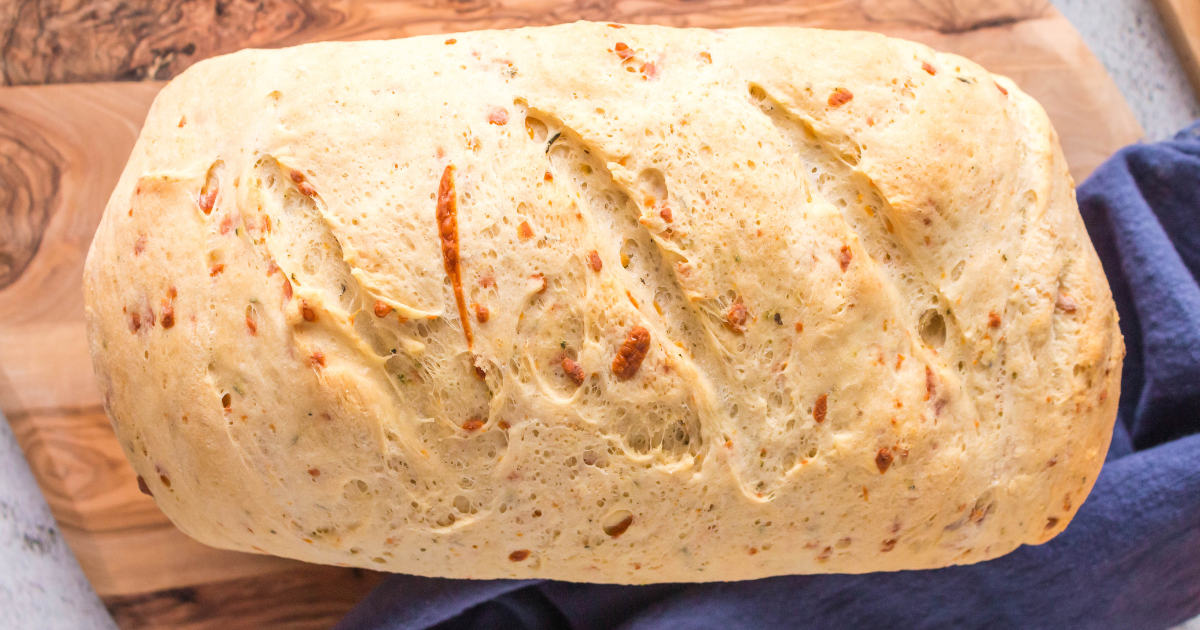 Top down view of a loaf of homemade cheese bread on a cutting board.