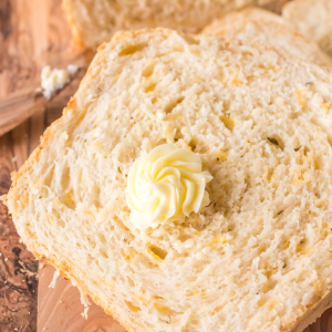 A slice of soft cheese sandwich bread with a pat of butter sitting on it.