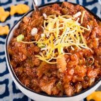 Top down view of a bowl of chili with no beans topped with cheese and onion.