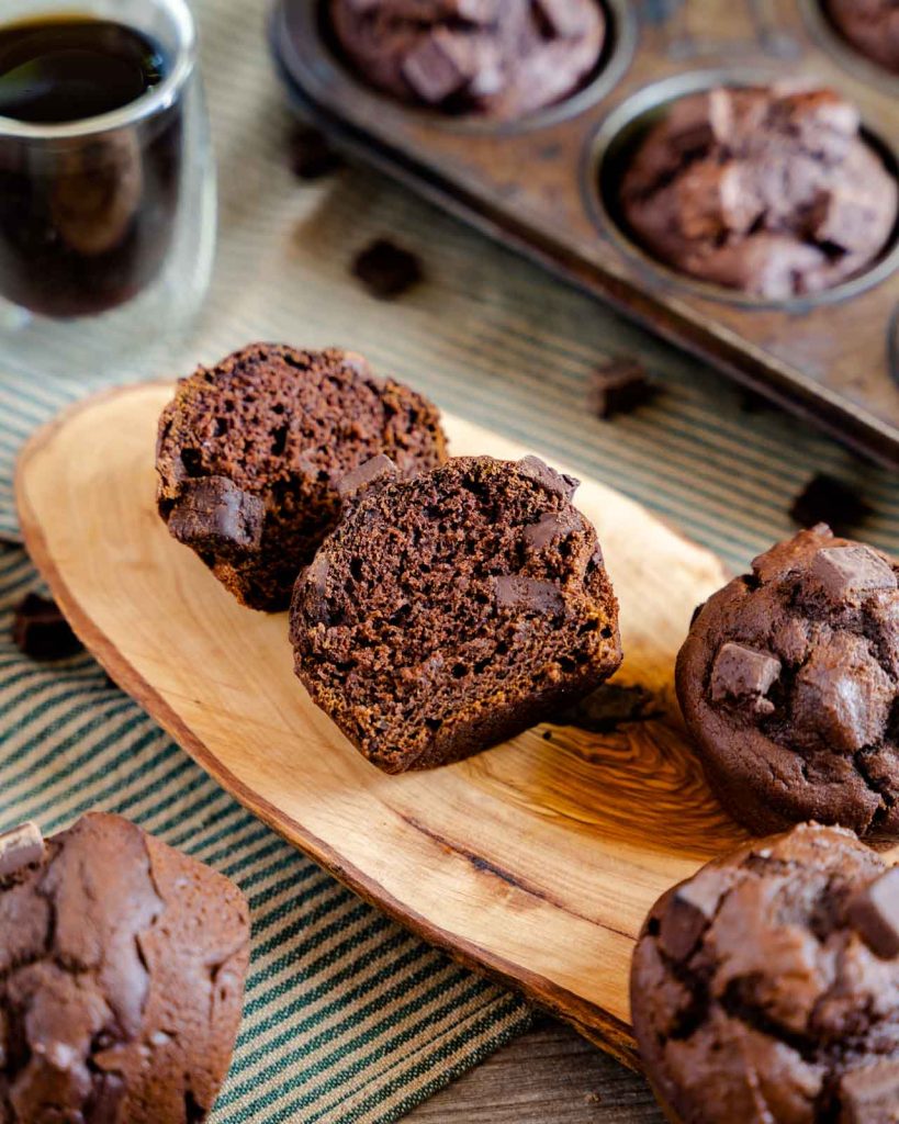 A chocolate muffin cut in half showing chunks of chocolate