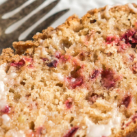 Sliced cranberry bread with dried cranberries topped with brown sugar streusel.